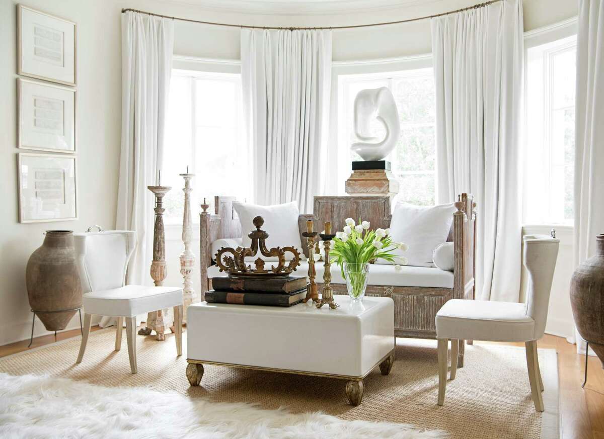 A seating area in the author’s own bedroom has a 19th century plinth — a base behind the settee — holding a vintage garden urn, a reference to the garden outside the trio of windows.