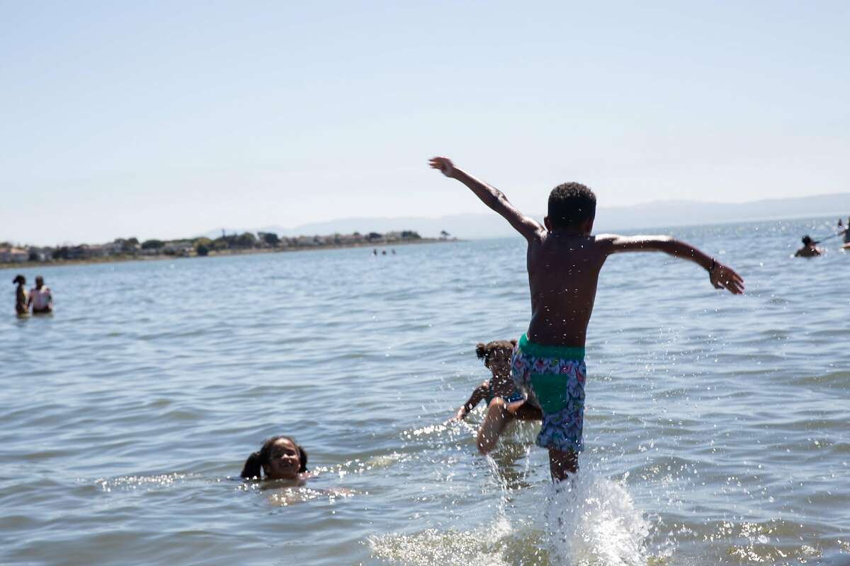 Kaden Jones (8) sprints into the water to play with his siblings Kailee (8) and Rylee Jones (8) to escape the heat at Alameda Beach in Alameda Calif. on Friday, August 14th, 2020