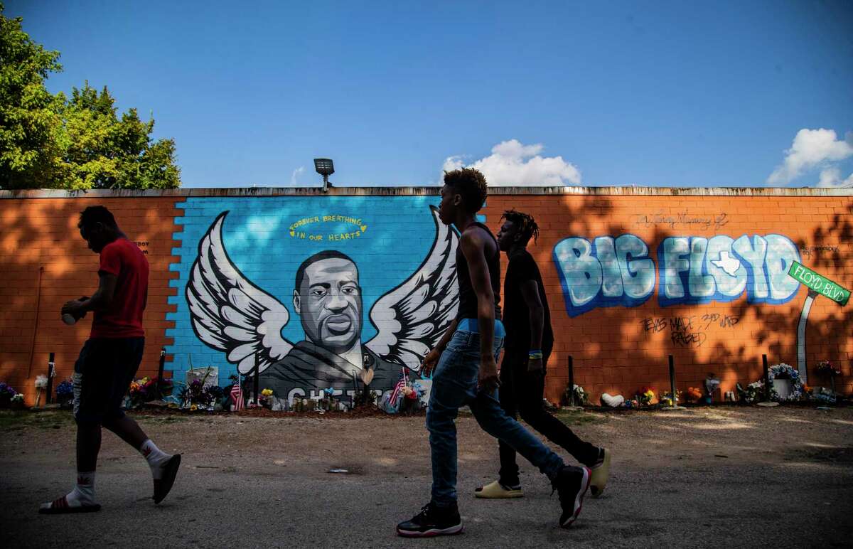 Three young men walk in front of the George Floyd mural in the Third Ward on August 12.