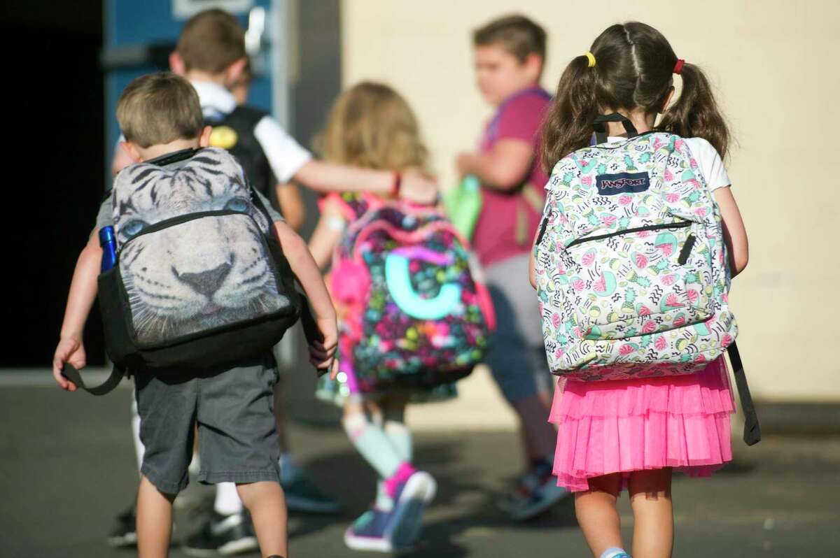 Students walk into Northeast School with their backpacks on during the first day of school in Stamford, Conn. on Thursday, Aug. 30, 2018.