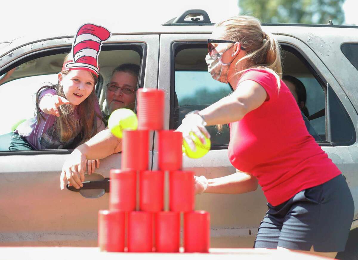 Emma Rose Moore throws a ball at stacked cans as part of Operation Backpack Drive-Thru at the East Texas Dream Center, Saturday, Aug. 15, 2020, in Splendora. The event provided more than 350 families in need with a backpack full of school supplies.