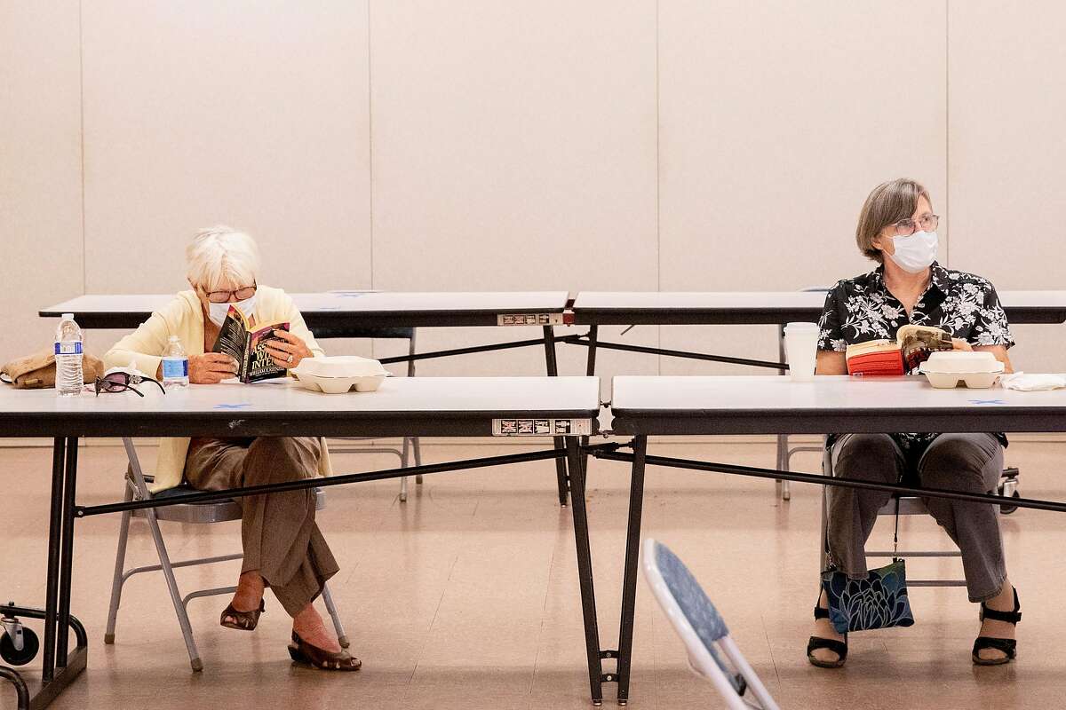 (From left) Martinez residents Patricia Adina and Claudine Thomas sit socially distanced from one another as they read at a cooling center set up inside Martinez Senior Community Center in Martinez, Calif. Saturday, August 15, 2020. Mulitple cities activated cooling centers at civic buildings and senior centers Saturday as triple digit temperatures are forecast for most locations across the Bay Area particularly in the East Bay and farther south. The COVID-19 pandemic has added extra precautions for check-in and assistance at cooling centers. Heat advisories are in effect throughout the Bay Area through the weekend.