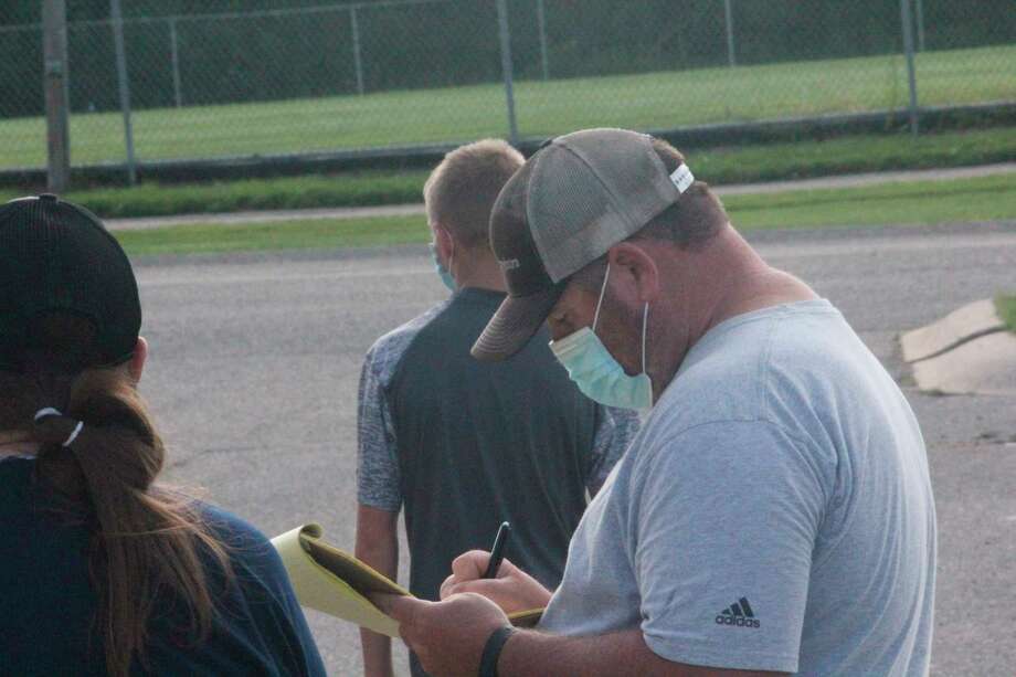 Reed City football coach Scott Shankel writes down some notes during an outdoor weight-lifting session at the school on July 31. (Pioneer photo/John Raffel)