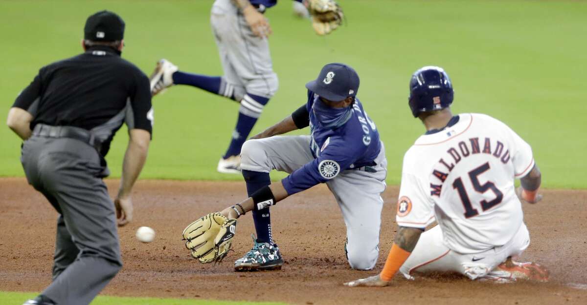 The throw is late to Seattle Mariner's second baseman Dee Gordon (9) as Houston Astros catcher Martin Maldonado (15) slides safely into second base with a steal, during the fourth inning of a baseball game Sunday, Aug. 16, 2020, in Houston. It was Maldonado's first steal since 2016, (AP Photo/Michael Wyke)