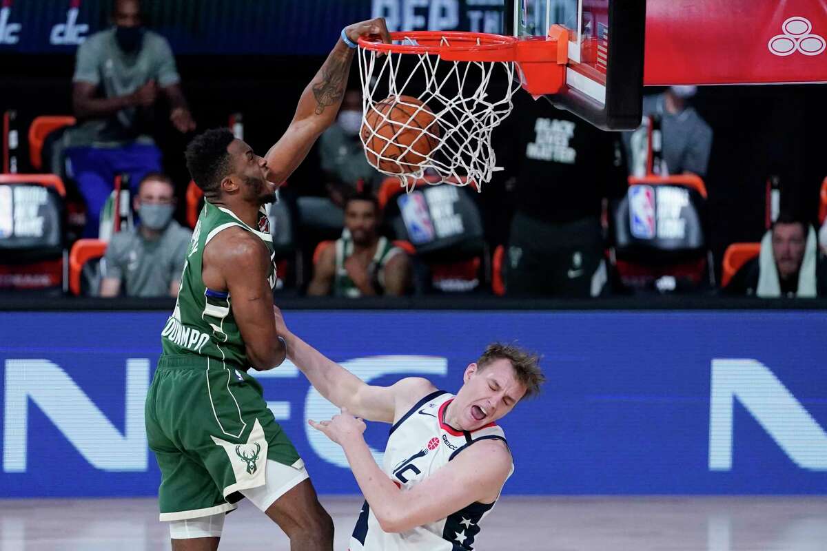 Milwaukee Bucks' Thanasis Antetokounmpo, left, slams a dunk over Washington Wizards' Anzejs Pasecniks (18) during the second half of an NBA basketball game, Tuesday, Aug. 11, 2020, in Lake Buena Vista, Fla. (AP Photo/Ashley Landis, Pool)