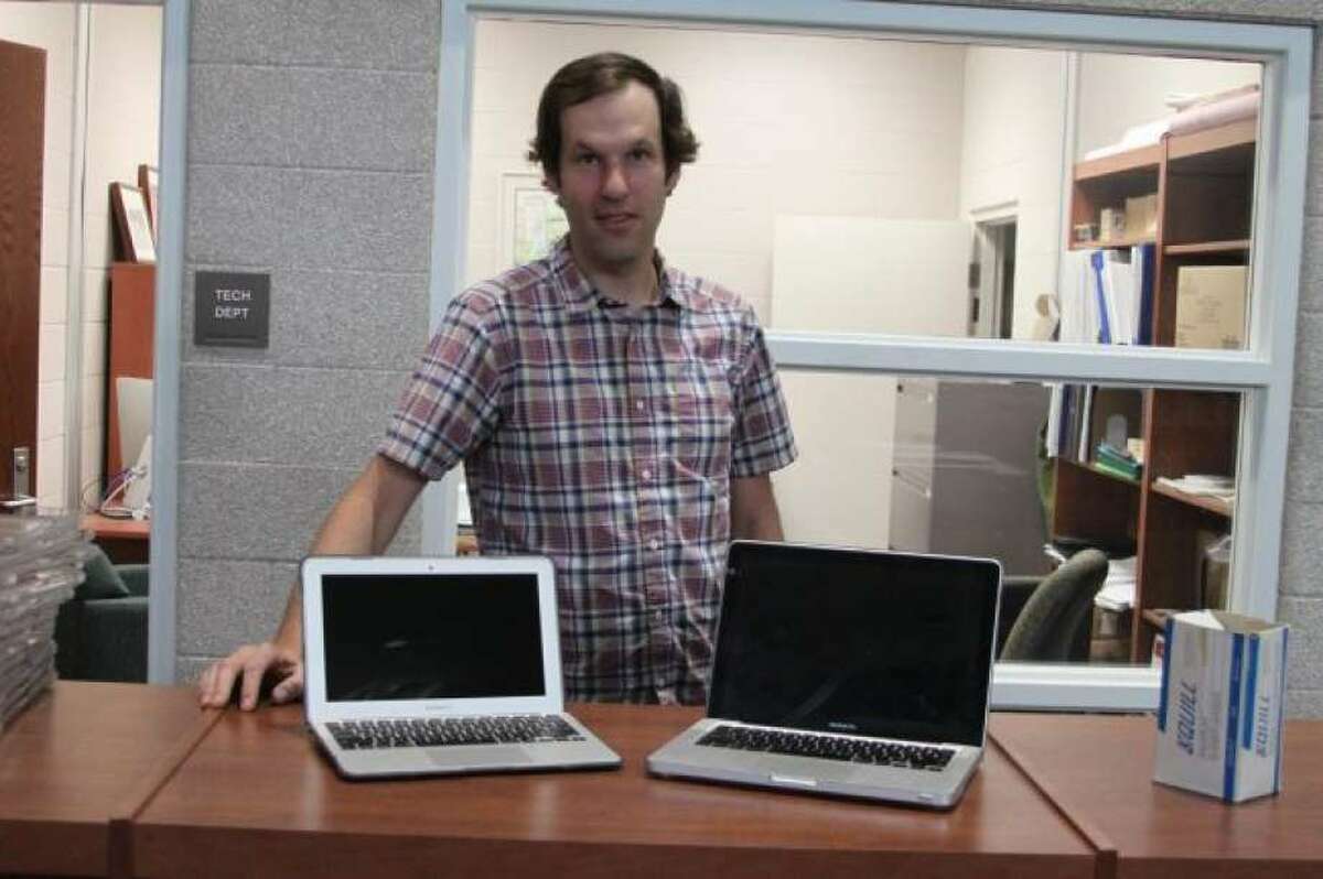 Manistee Area Public Schools technology director Ken Blakey-Shell shows off one of the 11-inch screen laptops next to the older 13-inch ones in this file photo. Blakey-Shell said that the district has been successful in getting devices back from students and repair rates have decreased. (File photo)