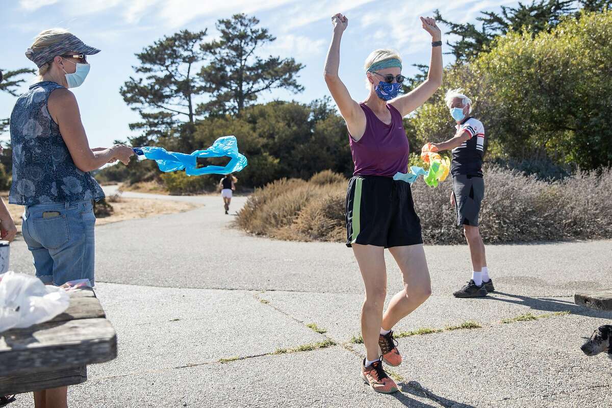 Phyllis Gardner and Gordon Priatko hold a ceremonial finish line while Robin Cohn crosses it at the end of Crosstown Trail in Candlestick Point Park in San Francisco, Calif. Saturday, August 15, 2020. Since October 2018, Cohn has ran every square inch of San Francisco streets, with numerous switch-backs totalling 3,000 miles. She ceremoniously finished her quest Saturday at Candlestick Point Park.