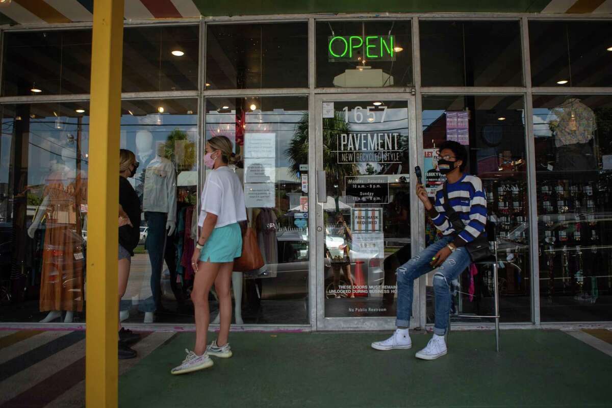 Customers wait in line to enter the Pavement thrift store in Houston. The store is limiting the number of customers inside, requiring masks, and offering hand sanitizer at the door.