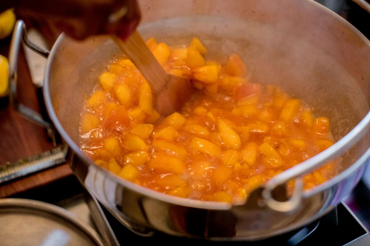 Shakirah Simley, master food preserver and director of the Office of Racial Equity for the city and county of San Francisco, makes peach preserves in her apartment in San Francisco on August 8, 2020. Simley turns off the heat before adding sugar to her peach preserves.