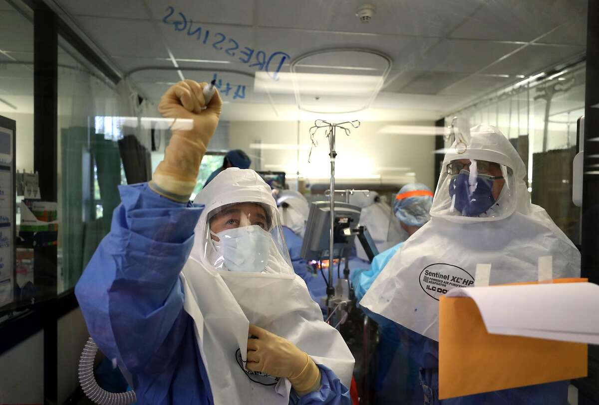 A nurse writes a note on a window as a team of doctors and nurses performs a procedure on a coronavirus COVID-19 patient in the intensive care unit (I.C.U.) at Regional Medical Center on May 21, 2020 in San Jose, California.
