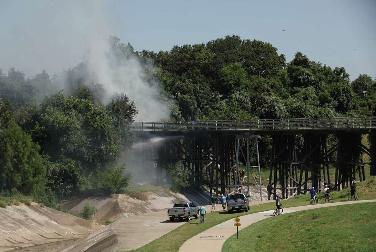 Firefighters work to extinguish a fire on a hike and bike trail bridge Wednesday, August 19, 2020, in the Heights neighborhood in Houston.