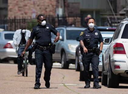 Houston police officers wearing face masks while responding to a double shooting at an apartment complex on the 5600 block of Royal Palms Street Tuesday, April 14, 2020, in Houston.