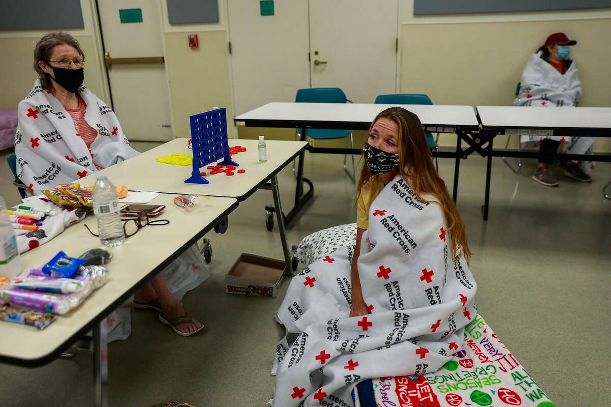 Evacuees Sharon Whitaker (left) and daughter Shawnee Whaley, 57, (center) take refuge at the Red Cross Shelter at the Ulatis Cultural Center after escaping the LNU Lightning Complex Fire in Vacaville , Calif., on Wednesday, August 19, 2020.