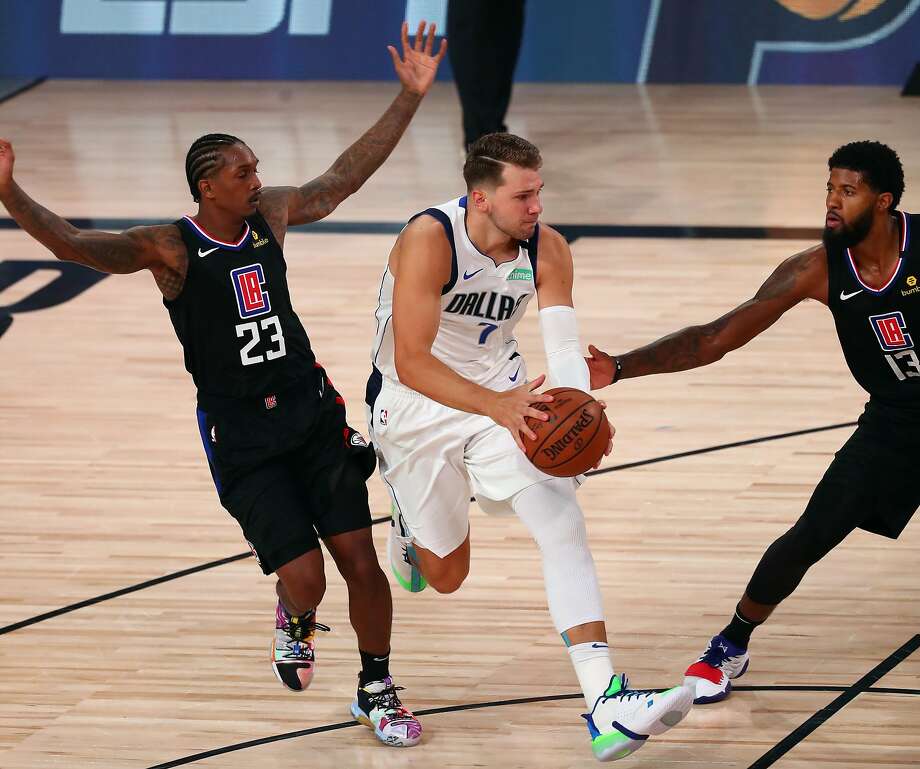 LAKE BUENA VISTA, FLORIDA - AUGUST 19: Luka Doncic #77 of the Dallas Mavericks drives between Lou Williams #23 and Paul George #13 of the LA Clippers during the second half in game two in the first round of the 2020 NBA Playoffs at AdventHealth Arena at the ESPN Wide World Of Sports Complex on August 19, 2020 in Lake Buena Vista, Florida. NOTE TO USER: User expressly acknowledges and agrees that, by downloading and or using this photograph, User is consenting to the terms and conditions of the Getty Images License Agreement. (Photo by Kim Klement-Pool/Getty Images) Photo: Pool / Getty Images