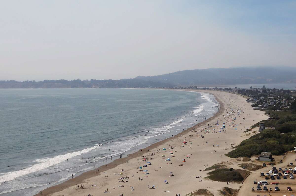 Crowds gather on Stinson Beach as smoke from the Woodward Fire in Point Reyes lingers overhead in Stinson Beach, Calif. Wednesday, August 19, 2020.