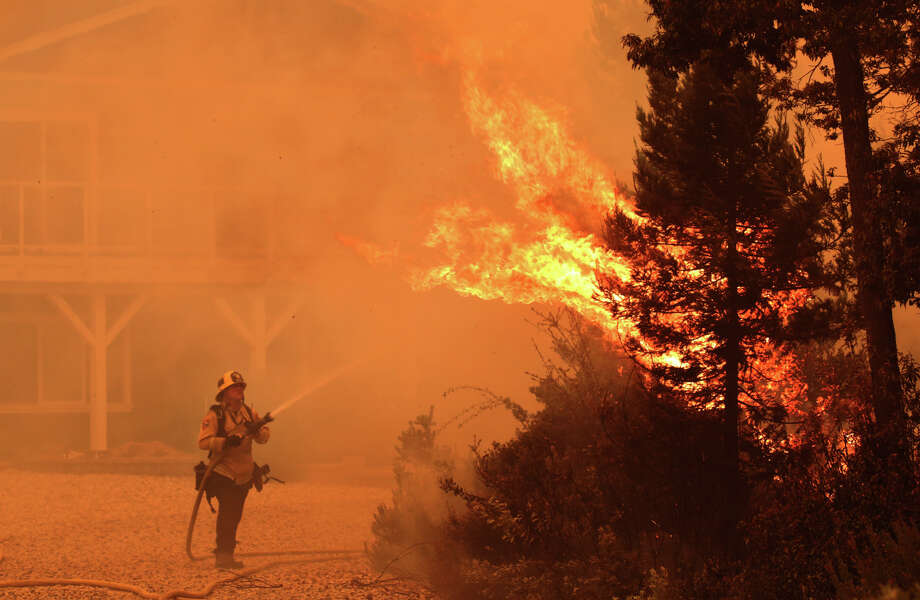 Firefighter David Widaman directs water onto a tree that had exploded in flame as a fire crew defends a house northwest of Santa Cruz, Calif., Wednesday Aug. 19, 2020. Photo: Shmuel Thler/AP Via Santa Cruz Sentinel