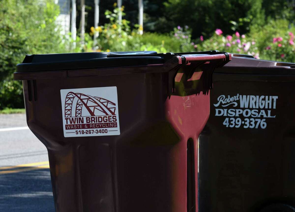 Trash cans from Twin Bridges Waste & Recycling and Robert Wright Disposal are seen along Kenwood Avenue on Thursday, Aug. 20, 2020, in Bethlehem, N.Y. Trash companies are in the midst of a marketing fight for suburban Capital Region customers. Twin Bridges recently offered a year of free trash pickup for new customers in Delmar. (Will Waldron/Times Union)