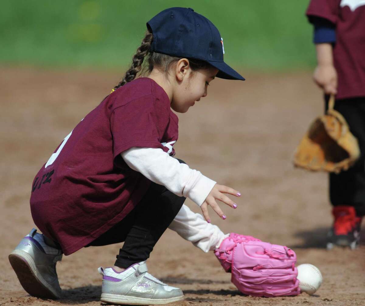 Five-year-old Alexis Ruiz fields a ground ball during Danbury Athletic Youth Organization T-Ball at the King Street Elementary School fields in Danbury, Conn. Saturday, May 3, 2014. A spike in COVID-19 cases has led the city to cancel fall youth sports