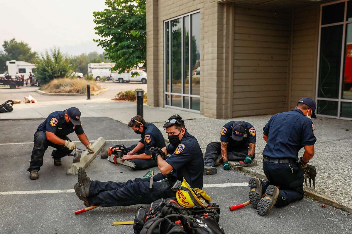 Firefighters with the CZU fire department sharpen their tools at the incident command center during the Lightning Complex Fire on Thursday, Aug. 20, 2020 in Scotts Valley, California.