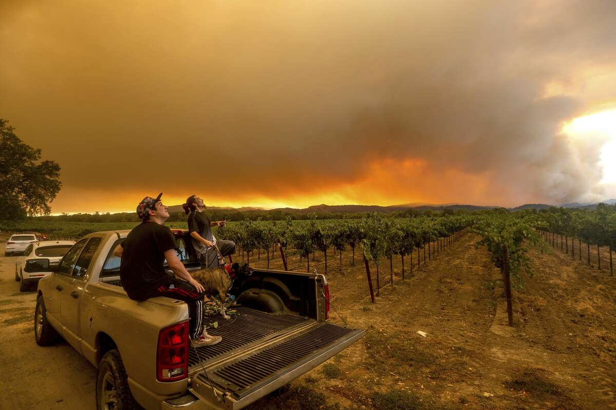 Thomas Henney, right, and Charles Chavira watch a plume spread over Healdsburg, Calif., as the LNU Lightning Complex fires burn, Thursday, Aug. 20, 2020. Fire crews across the region scrambled to contain dozens of wildfires sparked by lightning strikes.