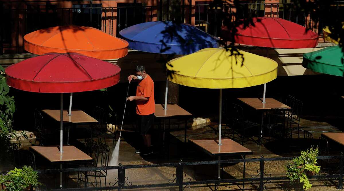 A worker wearing a mask to protect against the spread of COVID-19 power washes an exterior dinning area along the River Walk, Wednesday, Aug. 12, 2020, in San Antonio. (AP Photo/Eric Gay)