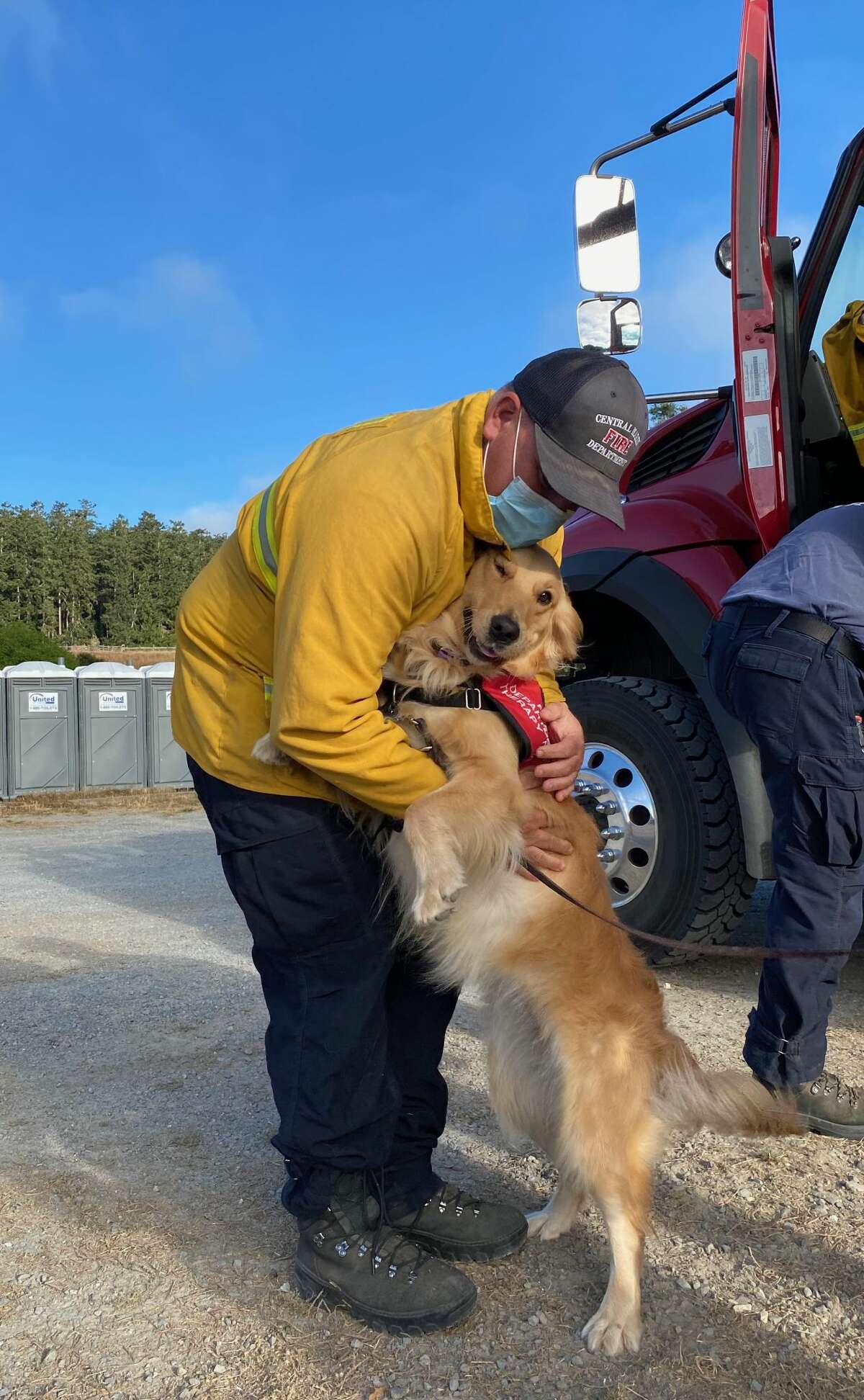Kerith gets a hug from a firefighter at the staging area of the Woodward Fire. She is a pet therapy dog popular among the firefighters in Marin County.