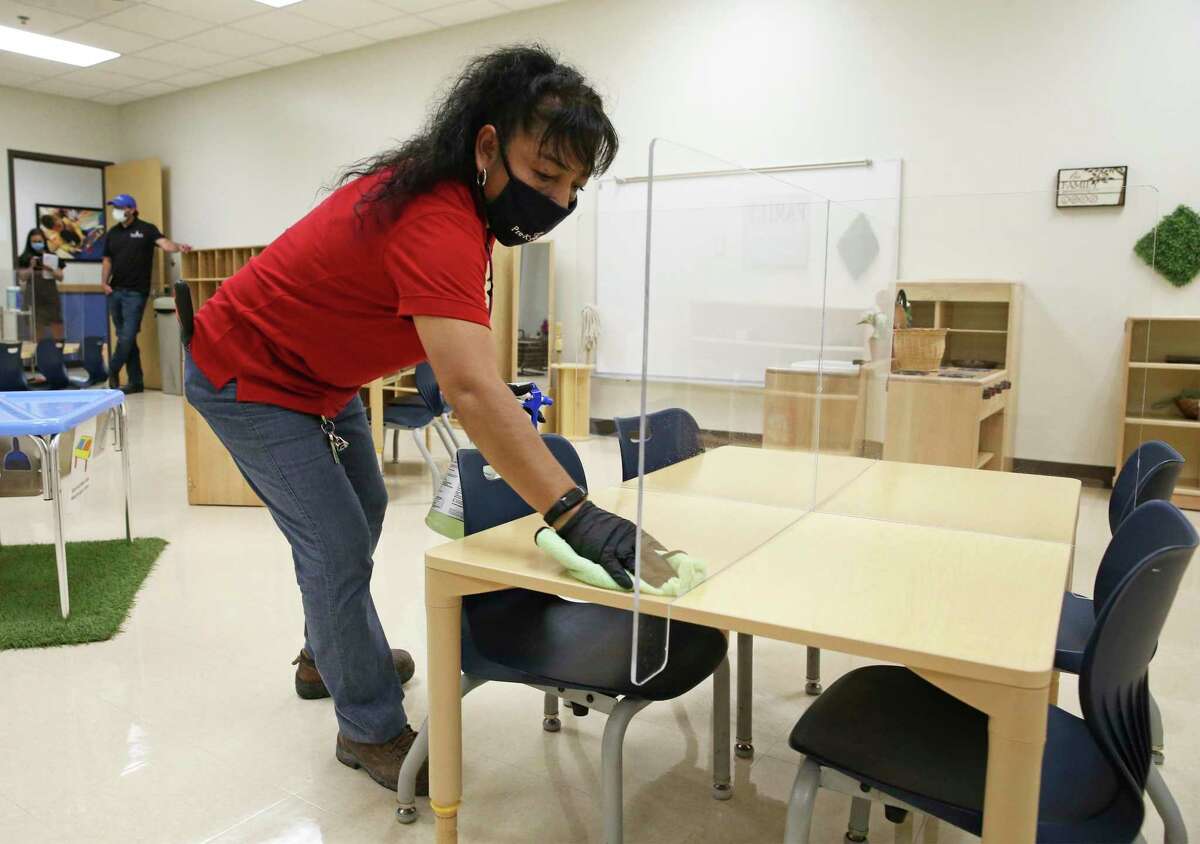 Evelia Garcia cleans desk spaces as Pre-K 4 SA CEO Sarah Baray shows measures taken by the Pre-K 4 SA North Center to combat spread of Covid-19 on Aug. 19, 2020.