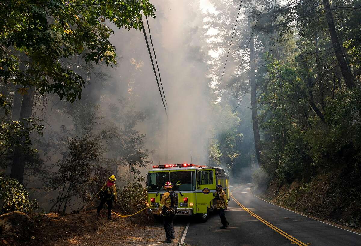 Firefighters work to put out smoldering embers from the CZU Lightning Complex Fire along Highway 236 near Boulder Creek, Calif. on Aug., 21, 2020.