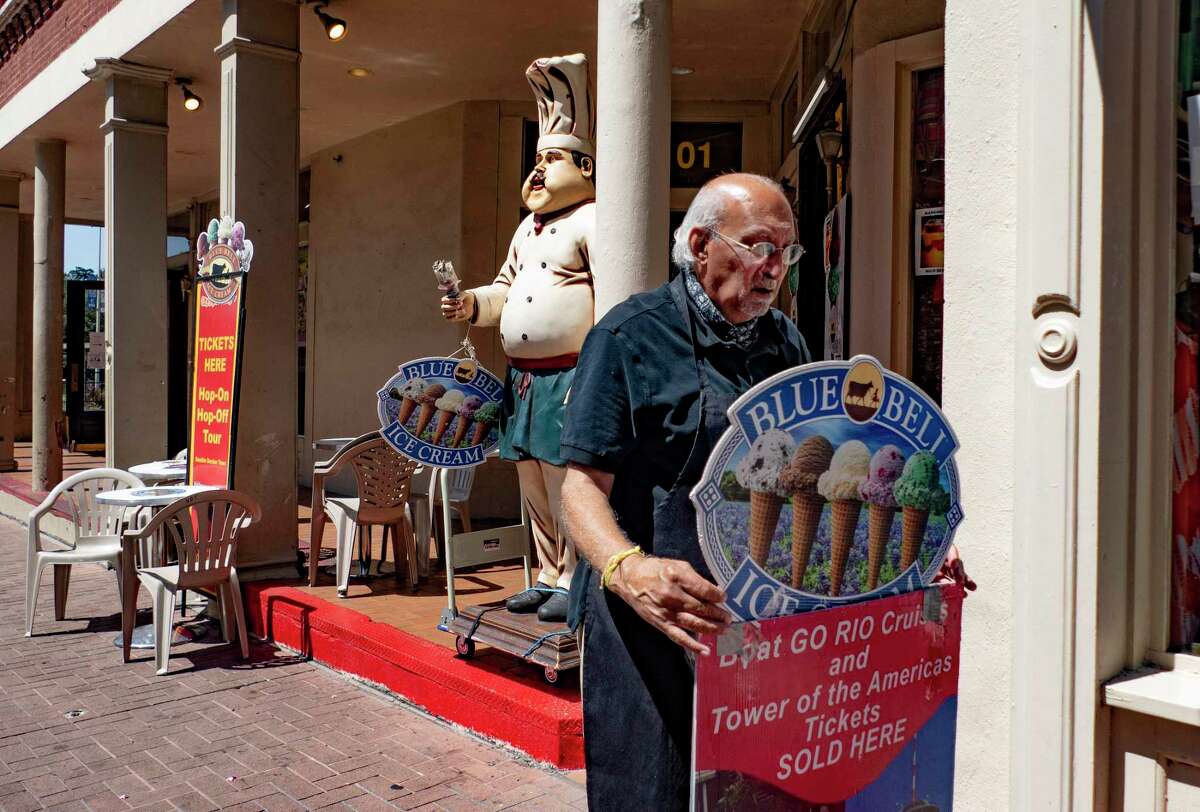 Kiran Bhalla, owner of The Unofficial Best of Texas on Alamo Plaza, which sells ice cream, hats and other souvenirs, adjusts a sign in front of his store on Thursday, Aug. 13, 2020. Bhalla said that his business is down 70 percent because of the coronavirus pandemic. He has had to cut the hours of his employees. “There is no hope on the horizon until the end of the year,” he said. “Conventions and Air Force graduations have all been cancelled.”
