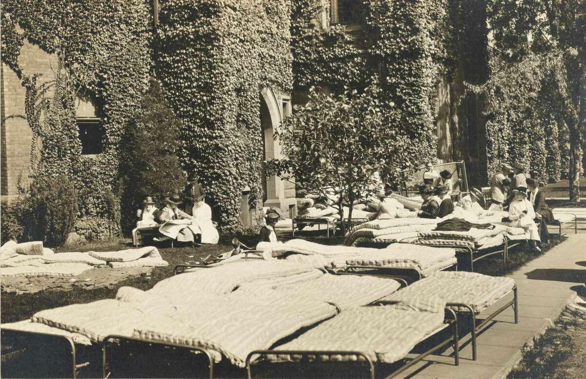 This is the only known photo of Middletown during the 1918 influenza pandemic. It shows Middlesex County Red Cross staff at the parish house behind Holy Trinity Church on Main Street, inspecting emergency hospital equipment.