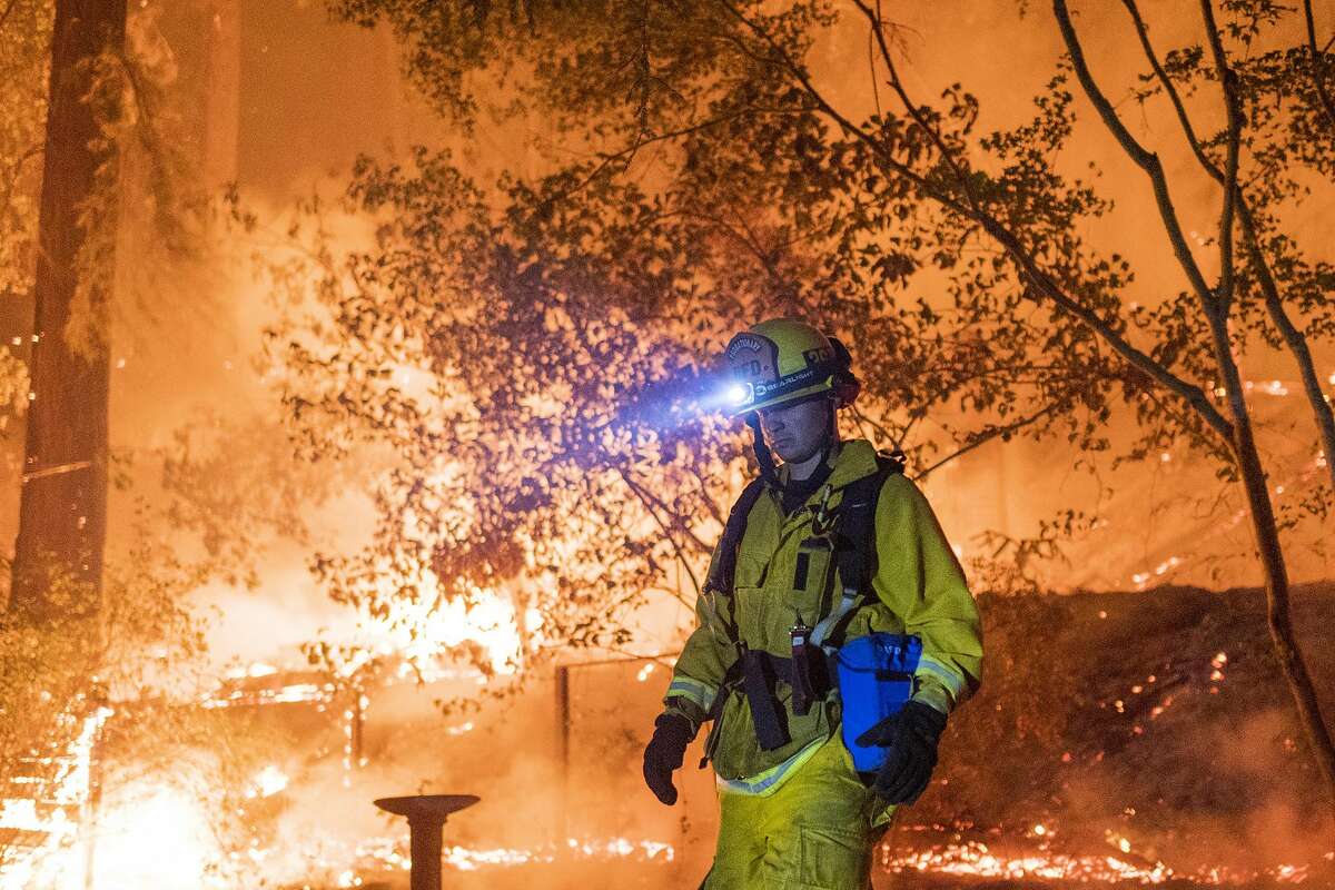 A firefighter assess the CZU Lightning Complex Fire burning behind a home on Madrone Avenue near Boulder Creek, Calif. on Aug., 21, 2020.