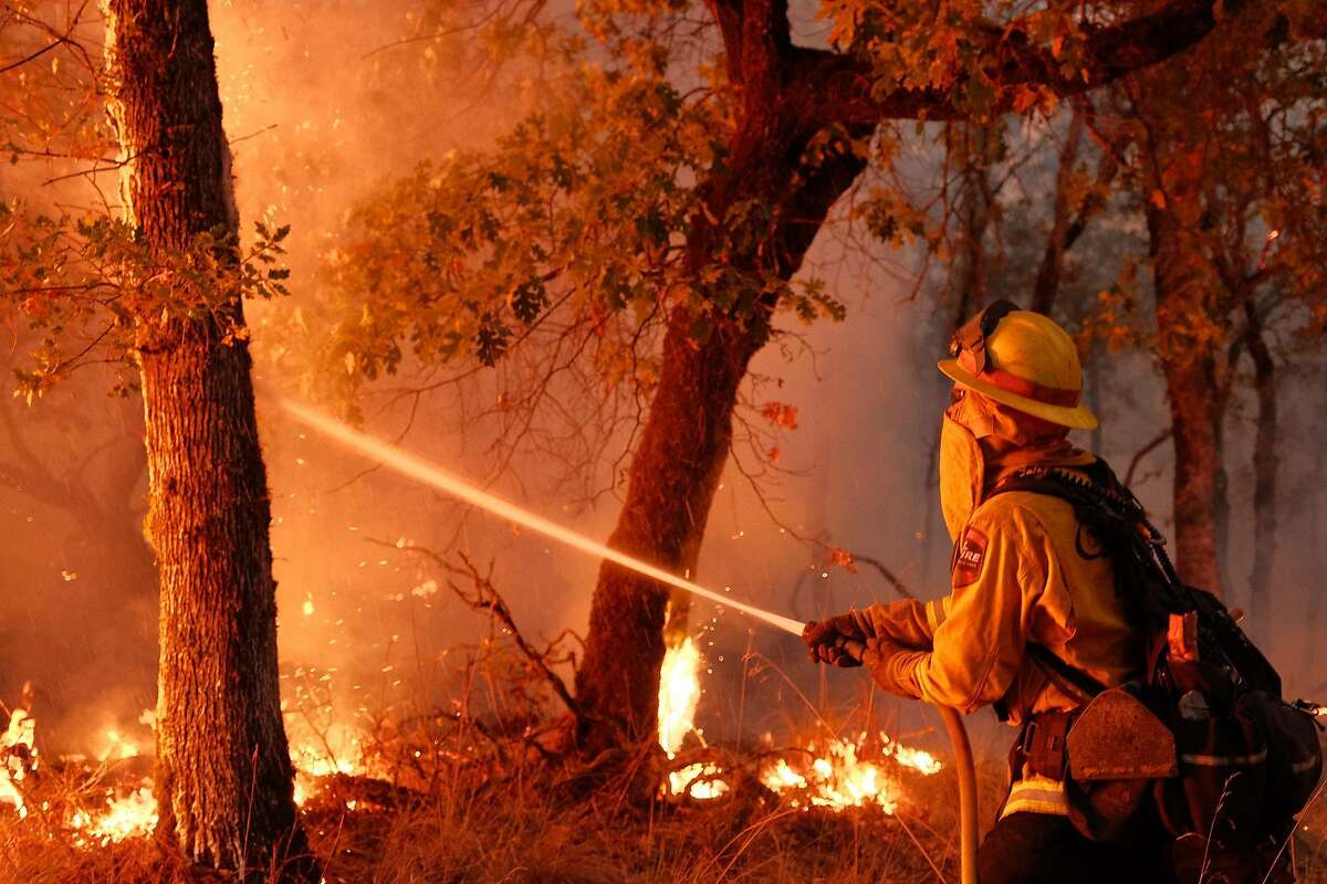A firefighter from Humboldt County battles a hot spot in a wooded area northeast of Calistoga on Friday, August 22, 2020.