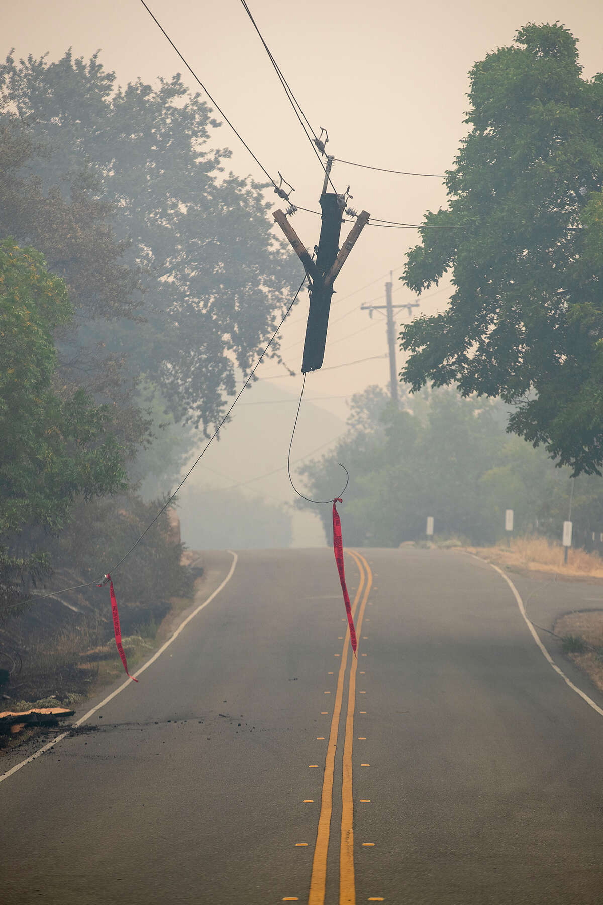 A utility pole damaged by the LNU Lightning Complex wildfire hangs over Gibson Canyon Road in Vacaville, Calif., on Thursday, Aug. 20, 2020. (Photo by Anda Chu/MediaNews Group/East Bay Times via Getty Images)