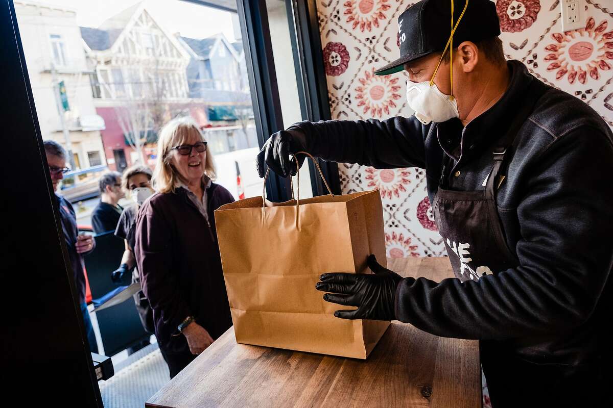 David Nayfield, co-owner of Che Fico Alimentari serves a takeaway meal to long time customer Peggy Cling who is celebrating her 50th wedding anniversary in San Francisco, Calif. on Saturday, March 21, 2020.