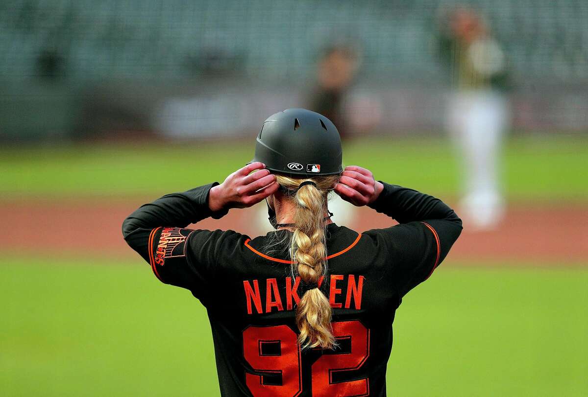 Giants first base coach Alyssa Nakken adjusts her mask in the coaches box as the San Francisco Giants played the Oakland Athletics in a summer exhibition game at Oracle Park in San Francisco, Calif., on Tuesday, July 21, 2020.