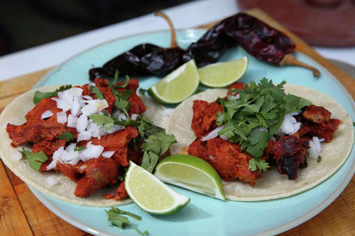 Al pastor tacos are served up with shaved onions, cilantro and lime wedges.