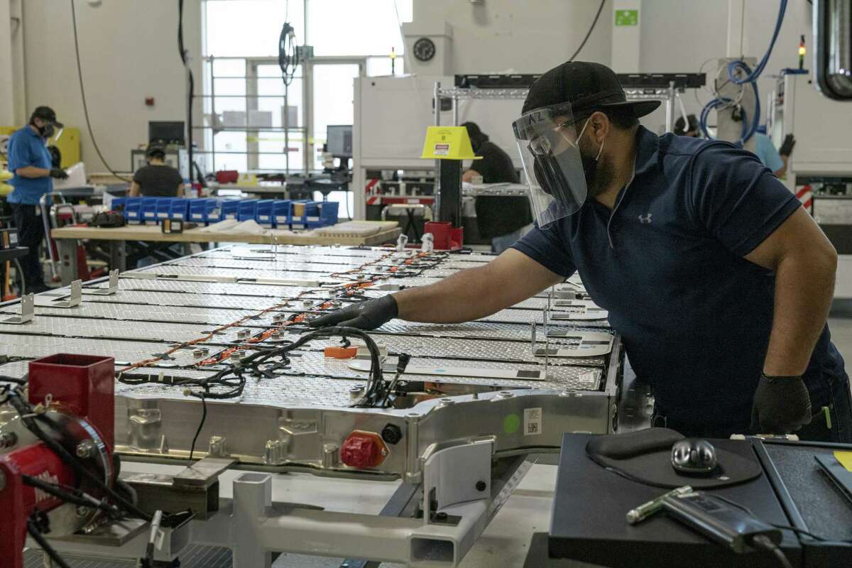A worker checks connections on a battery panel for the Lucid Air prototype electric vehicle, manufactured by Lucid Motors Inc., at the company's headquarters in Newark, California, U.S., on Monday, Aug. 3, 2020. The final specs and design of the Lucid Air are due to be unveiled at an event in September and executives say customers can now expect delivery of the first batch of Airs in spring 2021.