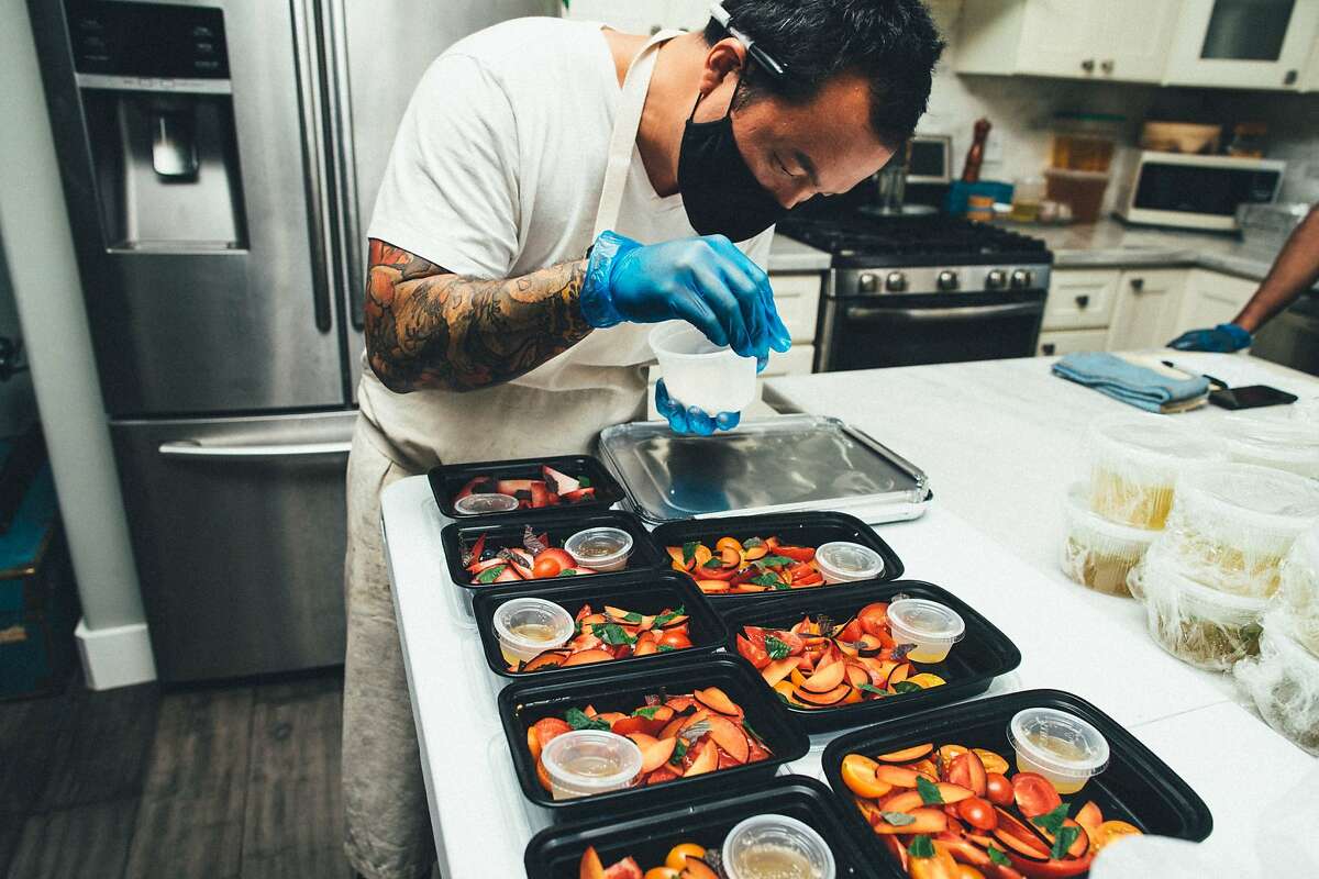 Hoang Le of Broke Ass Cooks packs side dishes for a chicken dinner in West Oakland. The pop-up was shut down by health inspectors because home kitchen operations aren’t permitted in Alameda County, but that could change in the coming months.