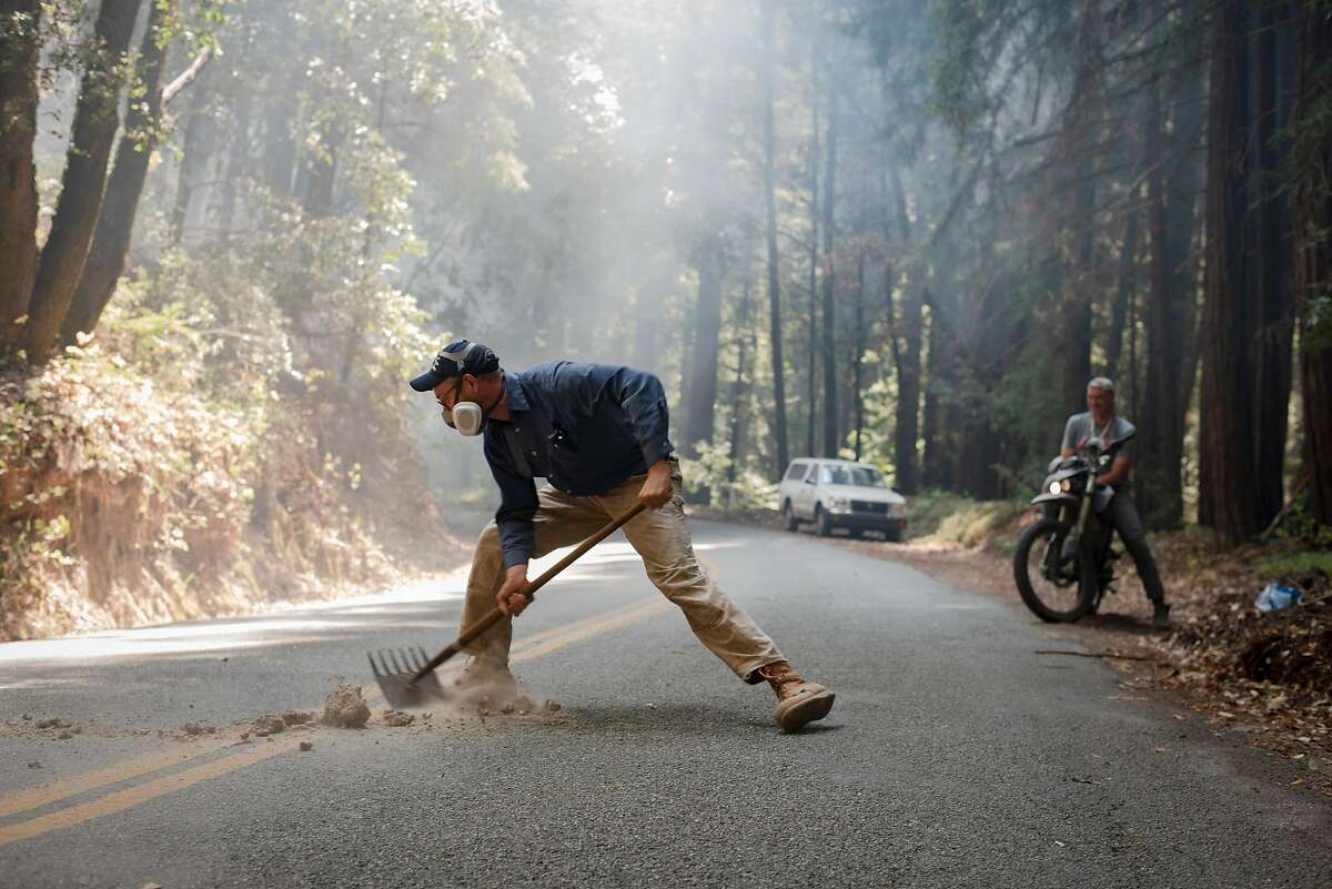 Jacob Kellner shovels fallen hot rocks back onto the other side of the Smith Grade, maintaining the fire break to defend the Boony Doon area from the CZU Lightning Complex Fire on Aug. 24, 2020. Kellner is part of a neighborhood that has banded together and stayed behind in an evacuation zone to defend their homes against the fire.