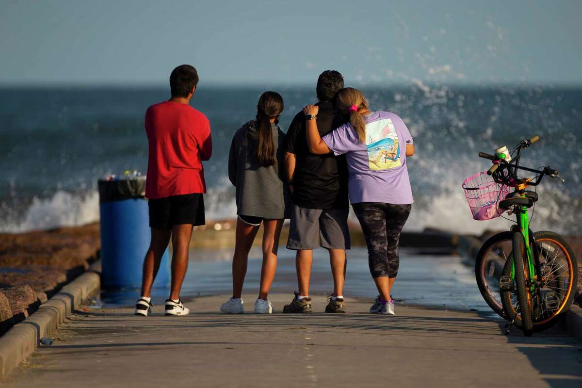 A family watches waves crash against a jetty as red flags go up on the beach and lifeguard stands are removed in anticipation of possible tropical weather later this week, Monday, Aug. 24, 2020, in Galveston.
