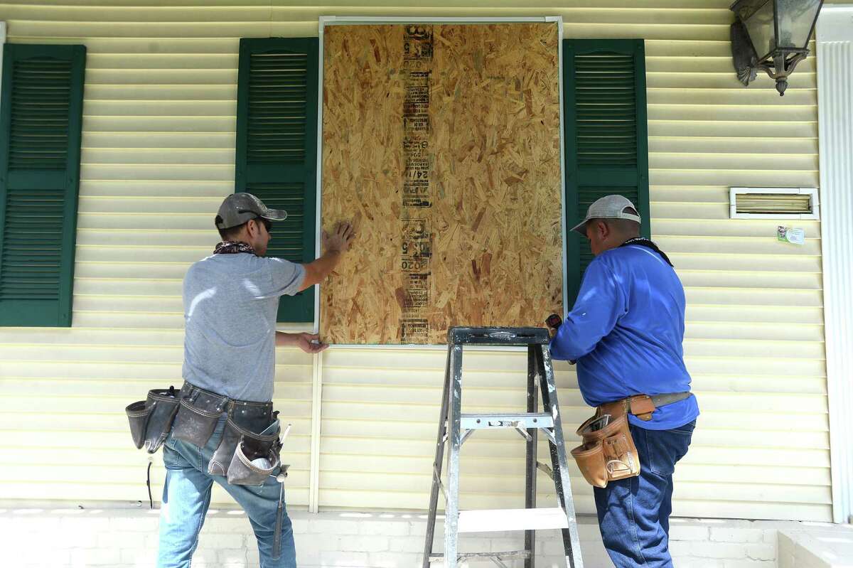 David Hernandez (left) and Pablo Garcia board up windows at the home of Francisco Ortega Monday as Ortega prepares his home in Port Arthur for Marco and Laura's hit to the region this week. Photo taken Monday, August 24, 2020 Kim Brent/The Enterprise