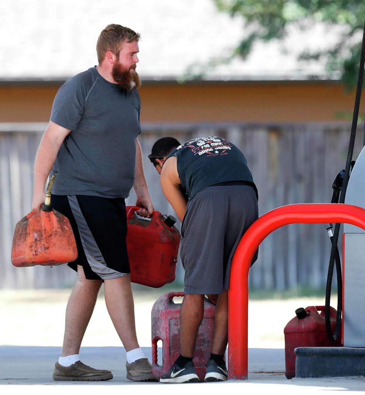 Colby Woody, left, carries fuel containers to his truck as Jacob Lewis finishes up at a gas station along South Loop 336 in preparation for Hurricane Laura, Tuesday, Aug. 25, 2020, in Conroe.