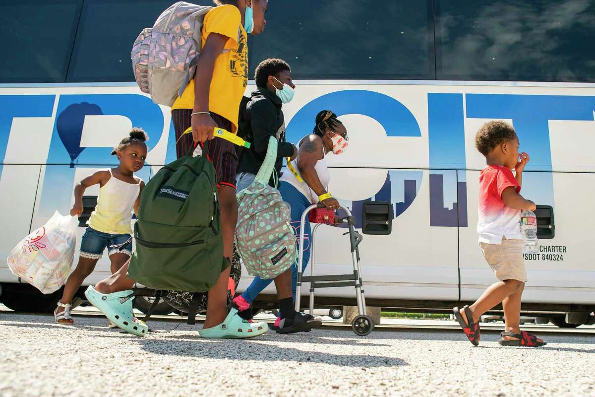 A family walks to a charter bus that will evacuate them from Galveston Island to Austin in anticipation of impact from Hurricane Laura, Tuesday, Aug. 25, 2020, at the Galveston Housing Authority offices in Galveston.