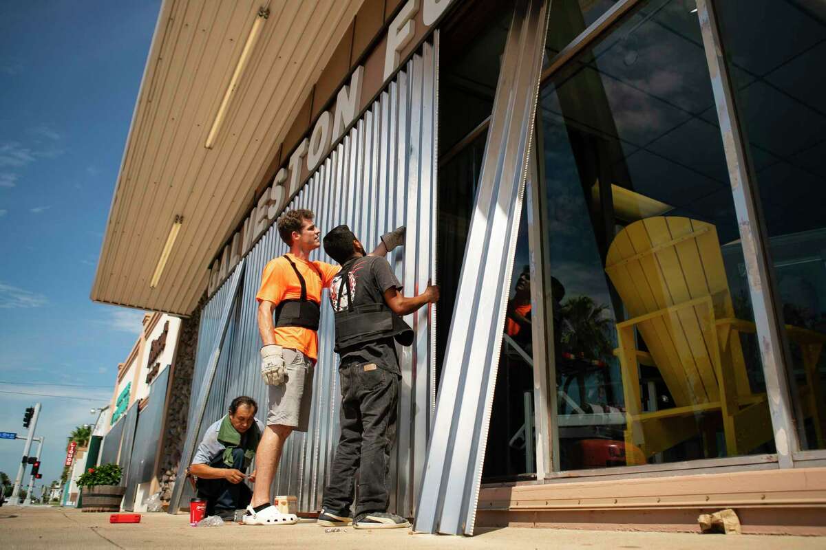 Employees of Galveston Furniture cover windows with metal as the island prepares for possible impact from Hurricane Laura, Tuesday, Aug. 25, 2020, in Houston.
