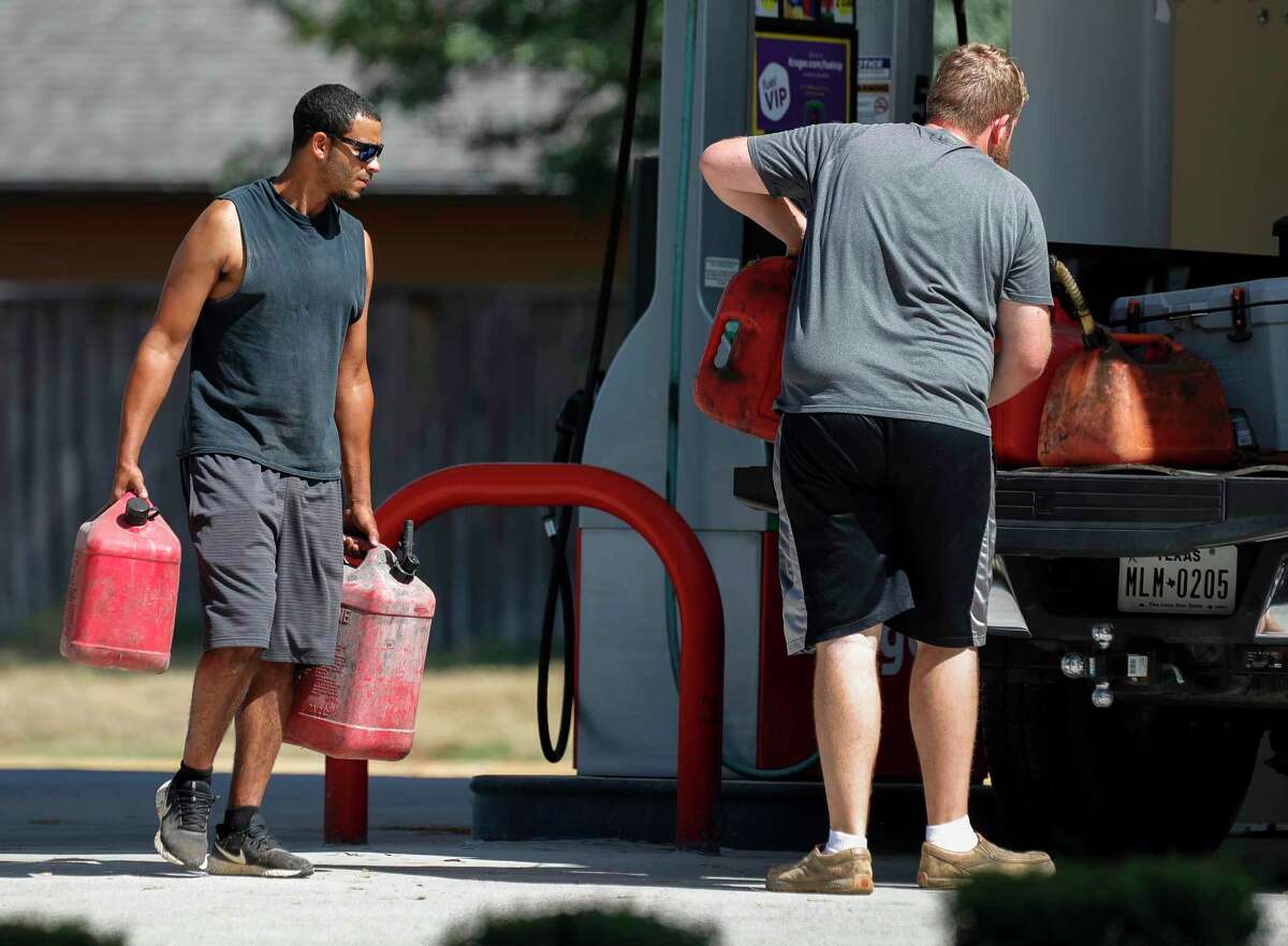 Jacob Lewis, left, helps Colby Woody carry filled-up fuel containers to the back of his truck at a gas station off South Loop 336 in preparation for Hurricane Laura, Tuesday, Aug. 25, 2020, in Conroe.