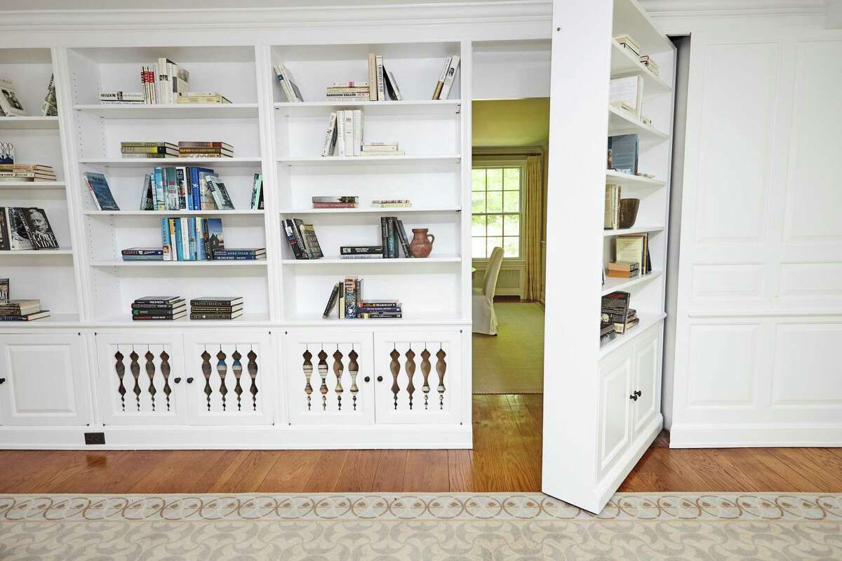 The family room features built-in shelving and a surprising section of the shelving that opens like a door into the dining room. Inside the stone and clapboard house with black shutters, the spacious formal living room features built-in bookshelves and the first of six fireplaces. Fireplaces are also found in the cavernous family room, the formal dining room, the library, and there are two on the full, finished walk-out lower level; one in the media room and one in the billiard room. The family room also features built-in shelving and a surprising section of the shelving that opens like a door into the dining room.