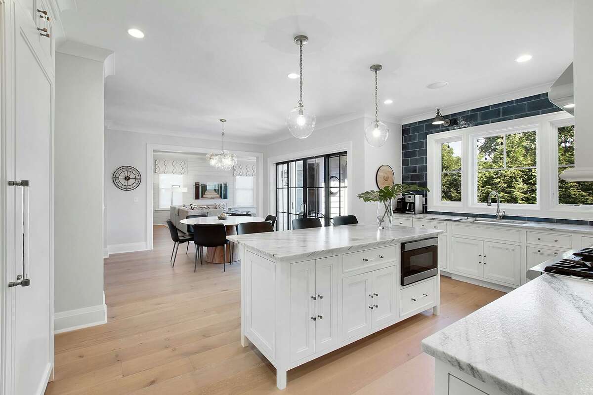 High-end appliances include a double size Sub-Zero refrigerator/freezer and a Thermador range with a pot-filler, and the eat-in area has sliding doors to the yard. While at home there are plenty of places to relax and enjoy the sophisticated yet casual living and entertaining opportunities afforded by this residence. It features two outdoor fireplaces; one on the bluestone patio and one on the rooftop deck. Inside, this house enjoys an open floor plan, generously proportioned rooms, and wide-board flooring in several rooms. The family room has a gas fireplace, coffered ceiling, shiplap walls, and a wet bar area with high gloss cabinetry, hammered sink, rubbed brass hardware, and stemware storage and display shelving. Off the foyer there is an office or library with a long wall of built-in shelving and cabinetry.