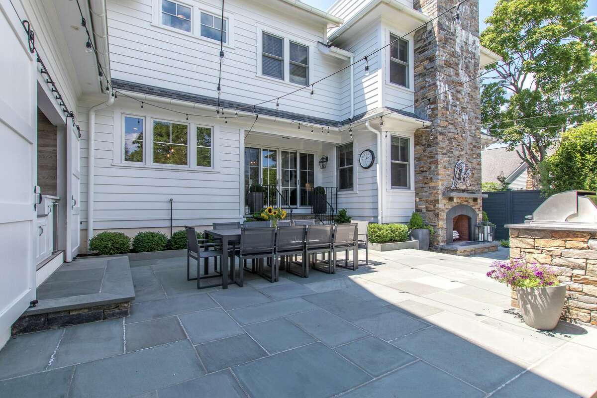 Dine al fresco on the large bluestone patio. The gourmet eat-in kitchen serves as the heart of this home. It features a custom center island/breakfast bar for three, marble counters, and large scale ceramic subway tile backsplash in a color reminiscent of the nearby water. High-end appliances include a double size Sub-Zero refrigerator/freezer and a Thermador range with a pot-filler. In the casual dining area there are sliding doors to the patio and fenced yard. Off the kitchen is a sizable mudroom with radiant heated flooring, a built-in bench, fully fitted closets, and the first of this home's two powder rooms. It also provides access to the attached two-car heated garage with electric car port. According to the agents the garage could actually accommodate a third vehicle.