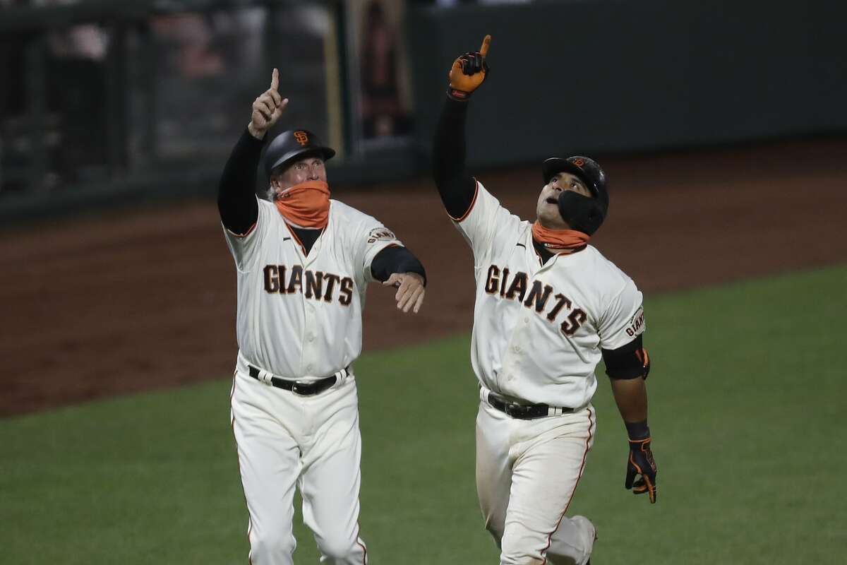 San Francisco Giants' Donovan Solano, right, celebrates with third base coach Ron Wotus after hitting the game winning home run against the Los Angeles Dodgers in the eleventh inning of a baseball game Tuesday, Aug. 25, 2020, in San Francisco. (AP Photo/Ben Margot)