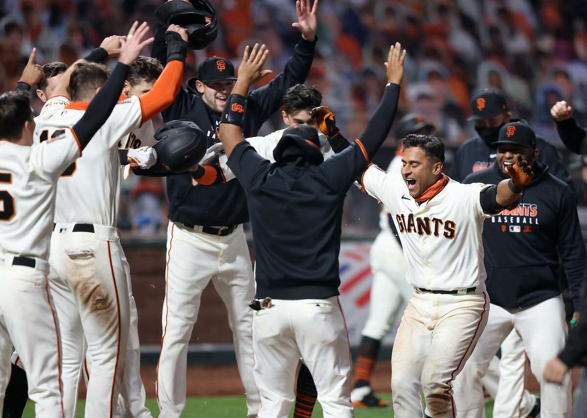 Donovan Solano #7 of the San Francisco Giants is congratulated by teammates after he hit a walk off home run to win the game in the 11th inning against the Los Angeles Dodgers at Oracle Park on August 25, 2020 in San Francisco, California.